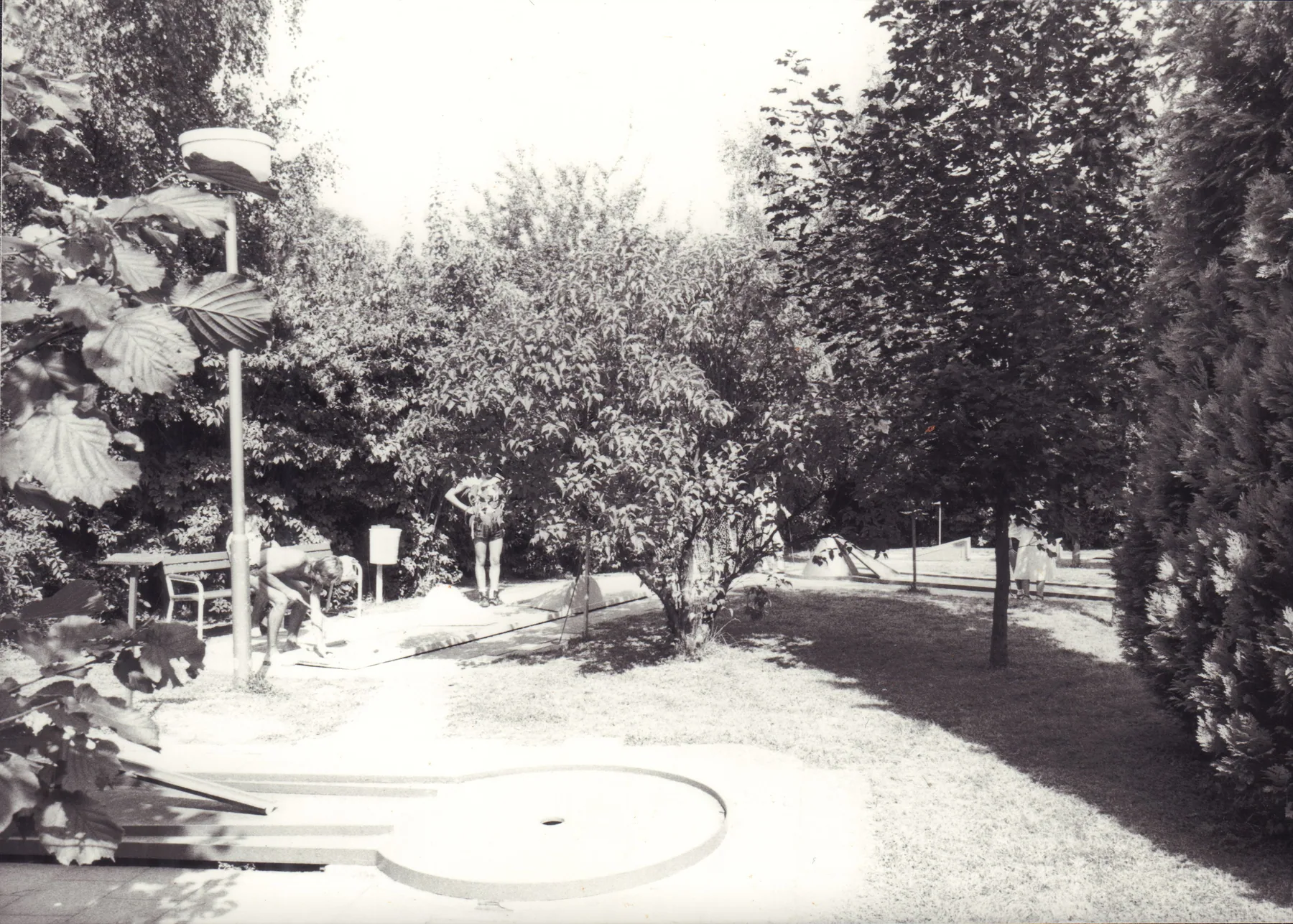 Historische Minigolfanlage mit Spielerinnen und Spielern zwischen Bäumen